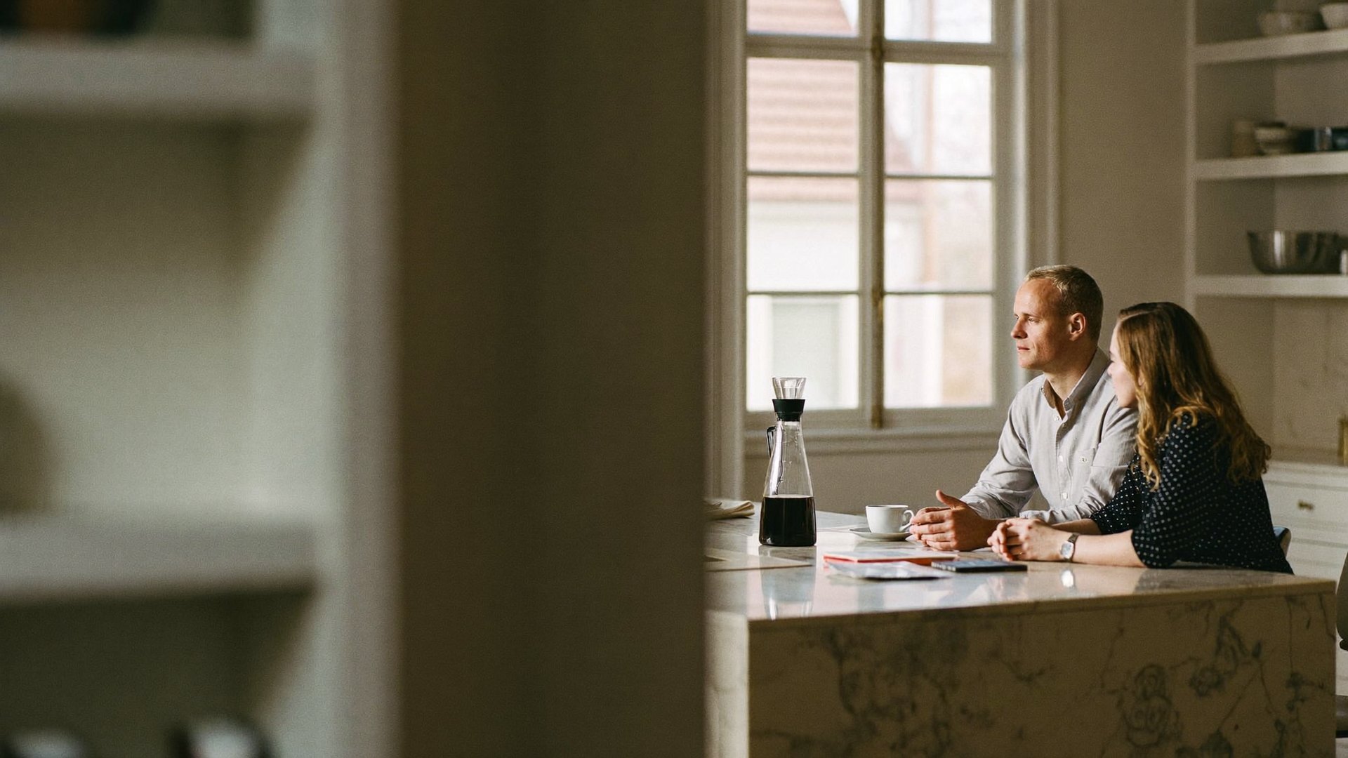 A couple who run a family business talking over coffee in their kitchen in the morning