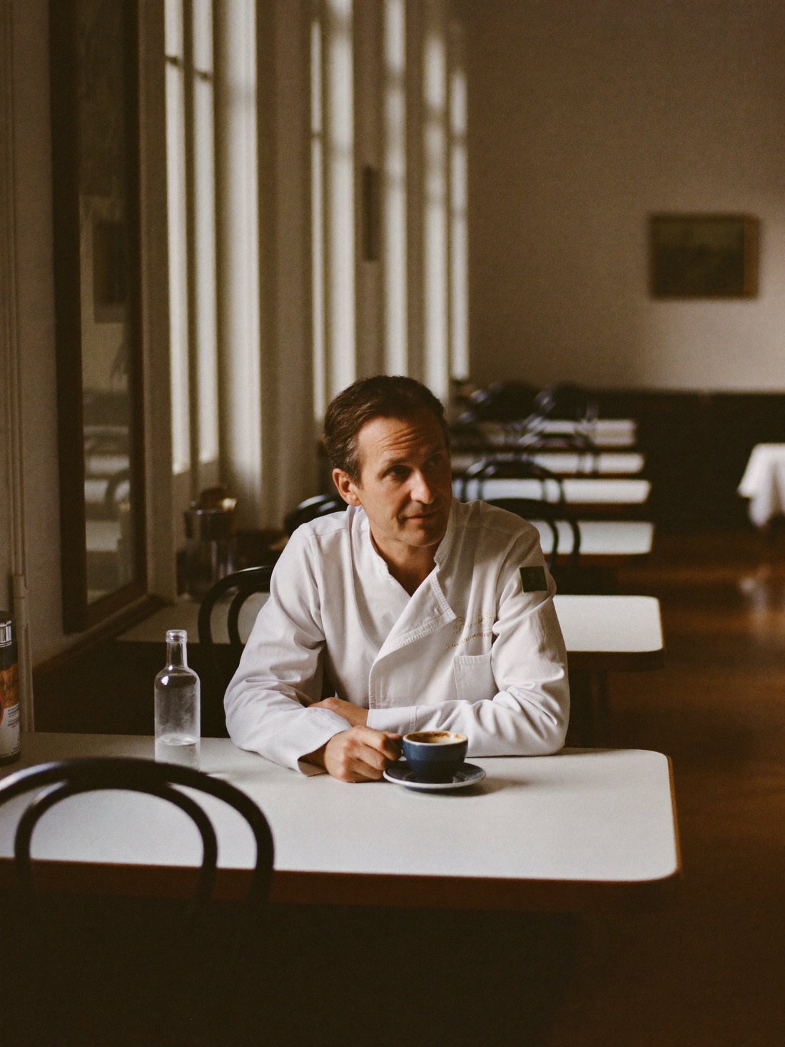A chef and restaurant owner resting in his empty dining room before service