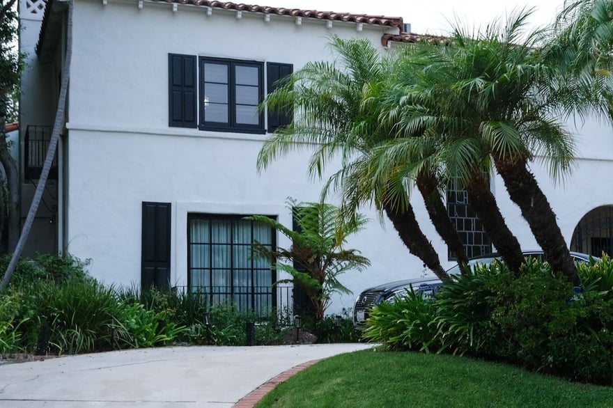A white stucco house with palm trees and greenery