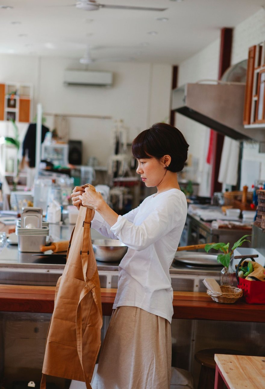 A restaurant owner tying an apron in a warm kitchen